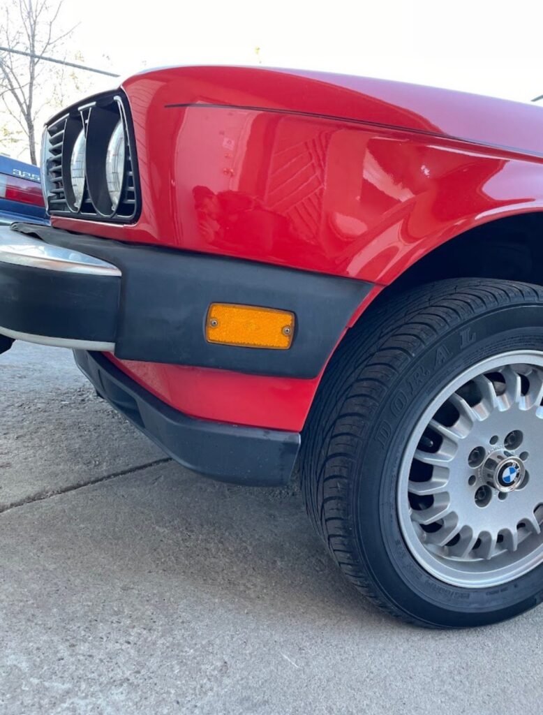 Close up of a red BMW front fender showing factory colour matched auto paint by Extreme Twist Collision in Santa Fe, New Mexico